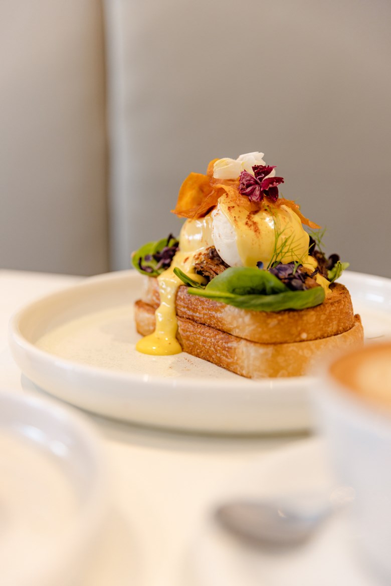 A brunch dish with toast and eggs sits on a table in a cafe.