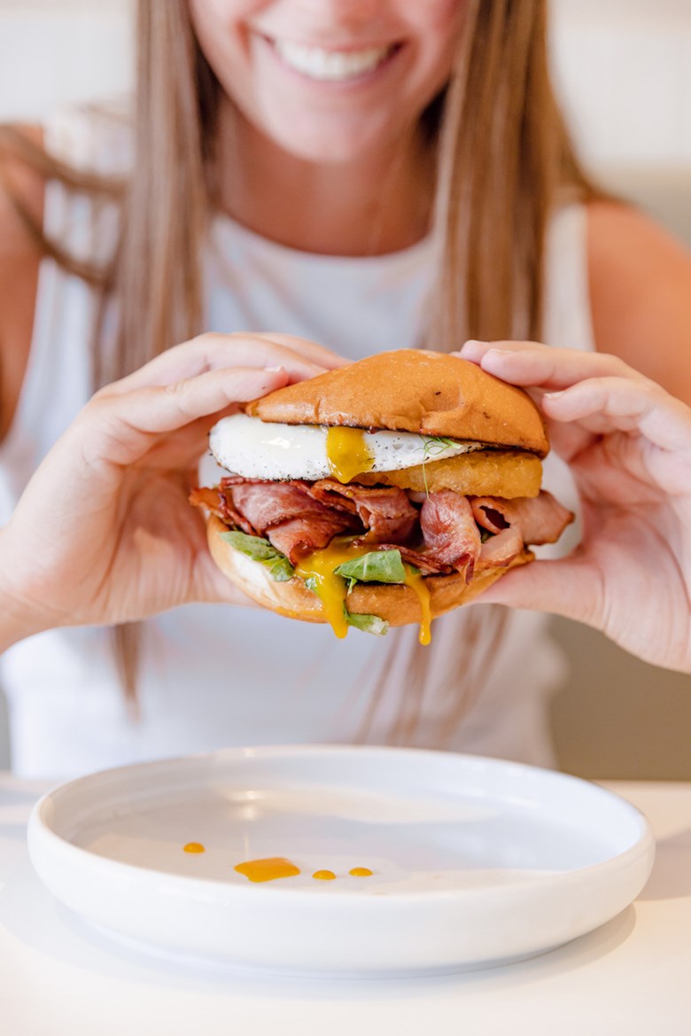 Woman holding burger with egg and bacon
